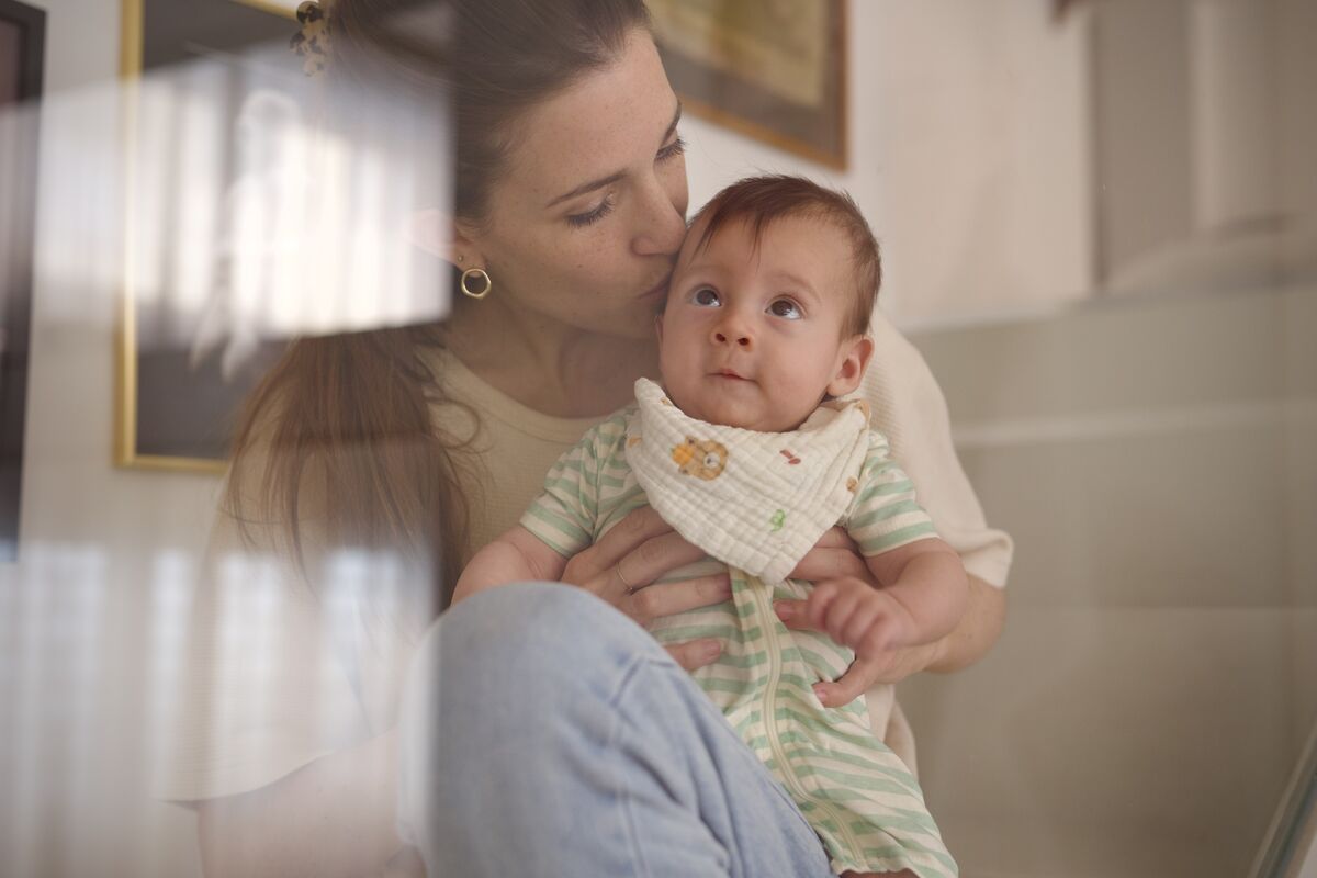 Mother kissing baby seen through soft glass reflection