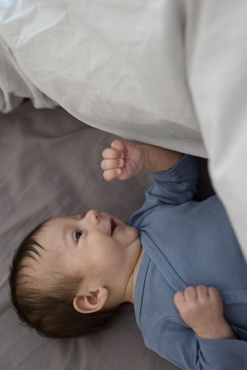 Baby peeking out from under a white sheet
