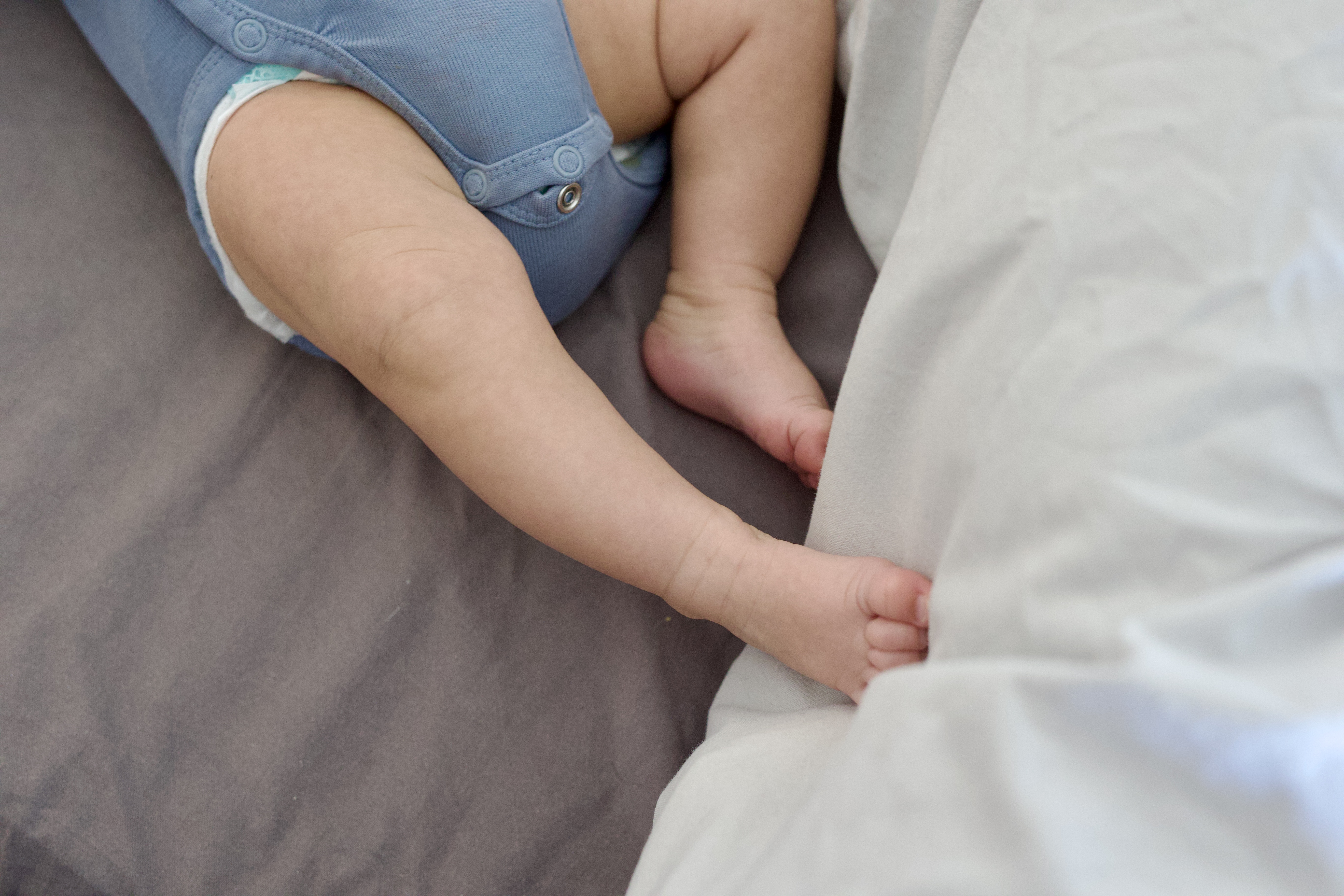Baby's tiny feet peeking out of blue onesie